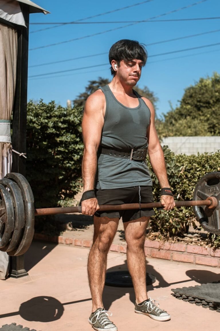 An adult man lifting a barbell outdoors, showcasing strength and fitness.